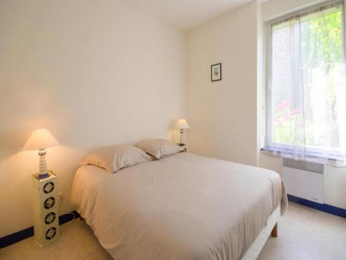 una camera da letto bianca con un letto e una finestra di Stone House by Les Godelins Beach a Gicquel