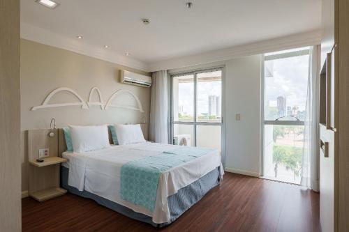 a bedroom with a large bed and a large window at Flat moderno Hotel Mercure Líder in Brasilia