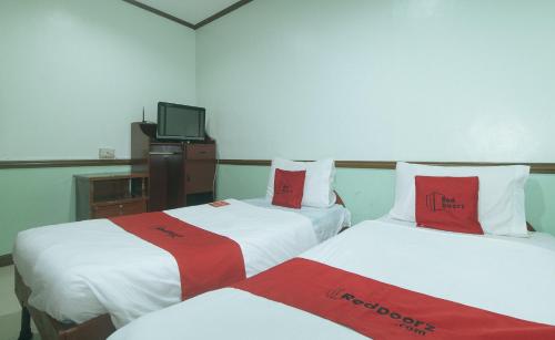 a hotel room with two beds with red and white sheets at RedDoorz at Maanyag Pension House Mandaue in Cebu City