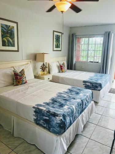 a bedroom with two beds and a ceiling fan at Paradise On The Rocks Hotel in Negril
