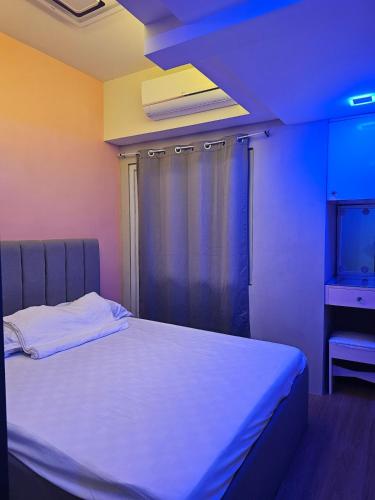 ein Schlafzimmer mit einem weißen Bett mit blauem Licht in der Unterkunft Pet friendly Condo in Timog with Balcony City view in Manila
