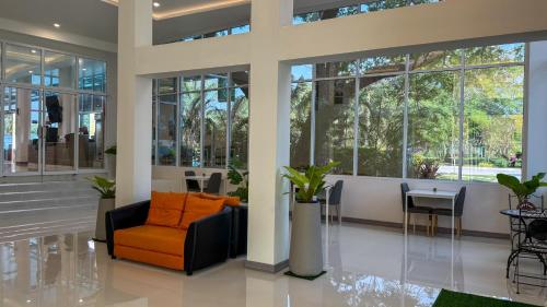 a lobby with an orange chair and a table at Baan Suan Khun Ta and Golf Resort in Ubon Ratchathani