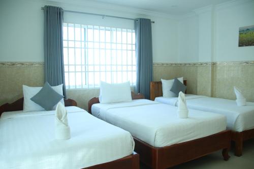 a room with two beds with white sheets and a window at White Corner Hotel in Phnom Penh