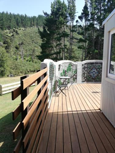 a wooden deck with a table and a chair on it at Old Mountain Road Retreat in Raglan