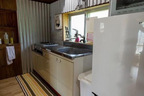 une cuisine avec un évier et un réfrigérateur dans l'établissement 猫宿 Muribushi-inn, à Motobu