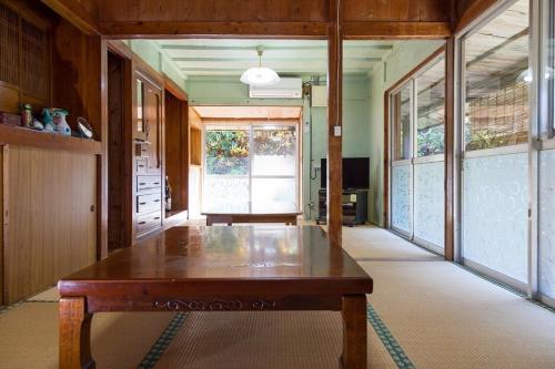 une grande chambre avec une table en bois au milieu dans l'établissement 猫宿 Muribushi-inn, à Motobu