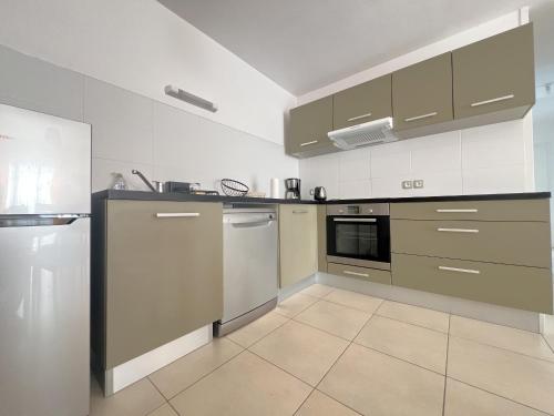 une cuisine équipée d'appareils en acier inoxydable et de placards gris dans l'établissement Appartement confortable proche centre-ville, 4 pers, parking inclus - FR-1-474-209, à Arcachon