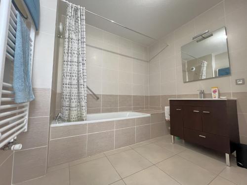 une salle de bain avec une baignoire, un lavabo et un miroir dans l'établissement Appartement confortable proche centre-ville, 4 pers, parking inclus - FR-1-474-209, à Arcachon