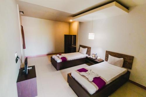 a hotel room with two beds and a tv at Bidari Hotel Lombok in Tjakranegara
