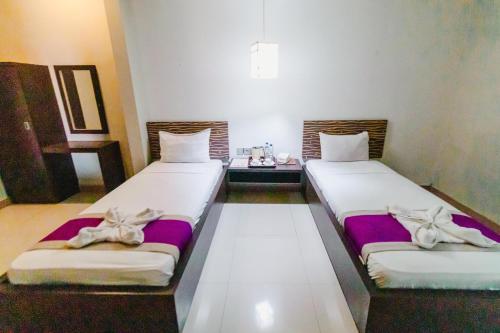 two beds in a room with purple sheets and bows at Bidari Hotel Lombok in Tjakranegara