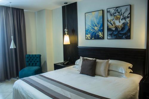 a hotel room with a bed and a blue chair at Hotel Las Cascadas in San Pedro Sula