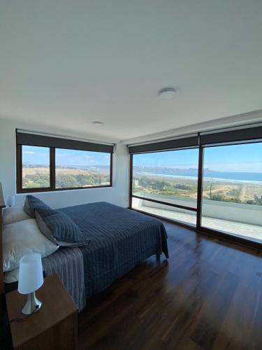 a bedroom with a large bed and large windows at Pingel Home Vista Mar in Valparaíso