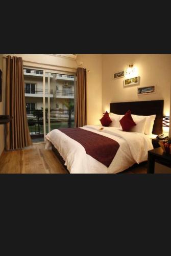 a bedroom with a large white bed with red pillows at Pearl suites at Omaxe entrenity in Vrindāvan