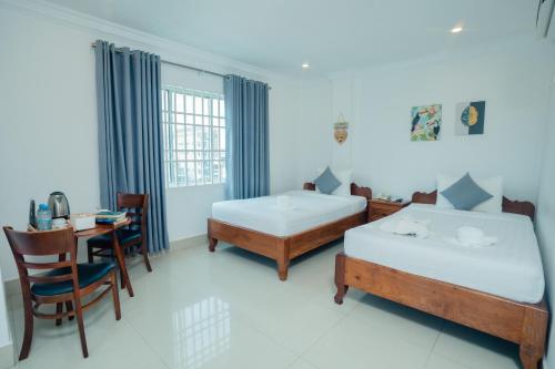 a bedroom with two beds and a desk and a table at White Corner Hotel in Phnom Penh