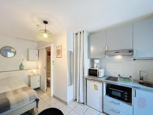 une petite cuisine avec un évier et un micro-ondes dans l'établissement Studio cosy avec terrasse, proche thermes et centre-ville - Lamalou-les-Bains - FR-1-451-189, à Lamalou-les-Bains