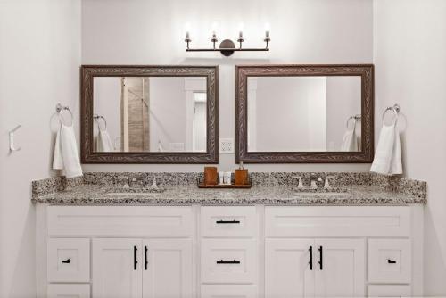 a bathroom with two sinks and two mirrors at Waterfront Treehouse on the Cape Fear with Dock in Rocky Point
