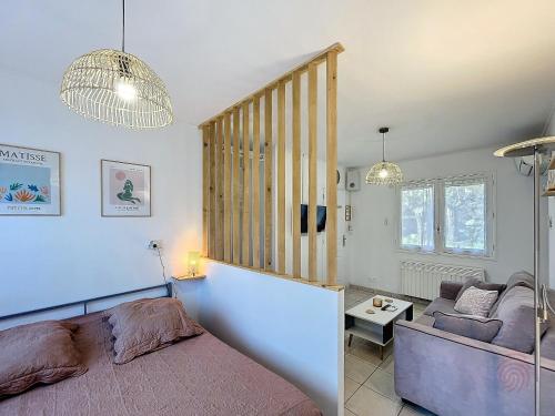 une chambre avec un lit et un canapé dans l'établissement Appartement F1 avec Terrasse et Clim, à 650m des Thermes - Lamalou-les-Bains - FR-1-451-191, à Lamalou-les-Bains