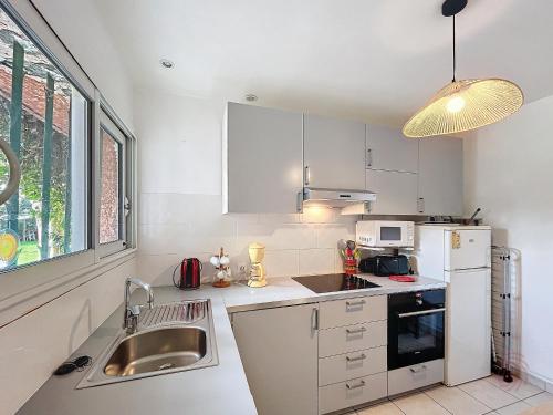 La cuisine blanche est équipée d'un évier et d'un réfrigérateur. dans l'établissement Appartement F1 avec Terrasse et Clim, à 650m des Thermes - Lamalou-les-Bains - FR-1-451-191, à Lamalou-les-Bains