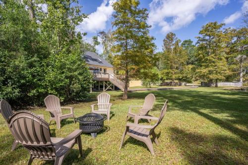 a group of chairs sitting in the grass in front of a house at Waterfront Treehouse on the Cape Fear with Dock in Rocky Point