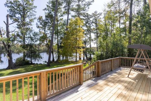 a wooden deck with a chair and an umbrella at Waterfront Treehouse on the Cape Fear with Dock in Rocky Point