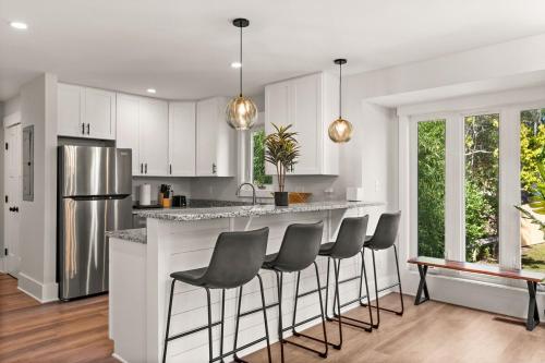 a kitchen with white cabinets and a bar with stools at Waterfront Treehouse on the Cape Fear with Dock in Rocky Point