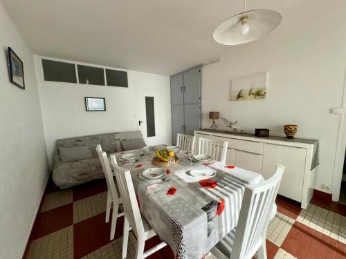 Il dispose d'une cuisine et d'une table à manger avec des chaises blanches. dans l'établissement Appartement lumineux à 50m de la plage avec balcon - 5 personnes, Saint-Jean-de-Monts - FR-1-323-298, à Saint-Jean-de-Monts