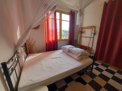 - une chambre avec un lit doté de rideaux rouges et d'un sol en damier dans l'établissement Appartement 4 pers à 50m de la plage avec terrasse calme et proche commerces à Argelès-sur-Mer - FR-1-776-51, à Argelès-sur-Mer