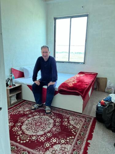 a man sitting on a bed in a room at Helipad View Hotel & Restaurant in Khātu