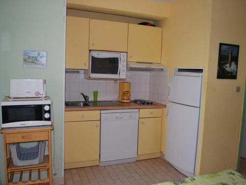 une petite cuisine avec des armoires jaunes et des appareils blancs dans l'établissement Le Lavandou T2 Cabine 4 personnes, à 10m de la plage avec parking - FR-1-803-90, au Lavandou