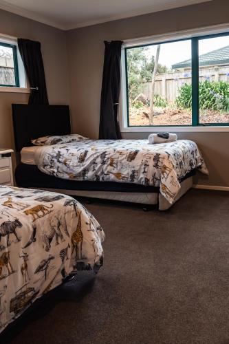 a bedroom with two beds and a window at Observation Holiday Home in Paraparaumu Beach