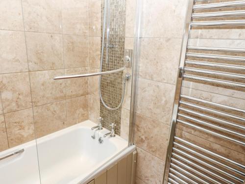 a bathroom with a shower and a bath tub at Castle Hill Cottage in Middleham