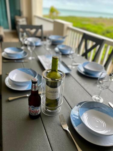 a table with plates and a bottle of wine on it at Seas the Day TCI -Sonos, Covered Balcony, hot tub in Wheeland Settlement