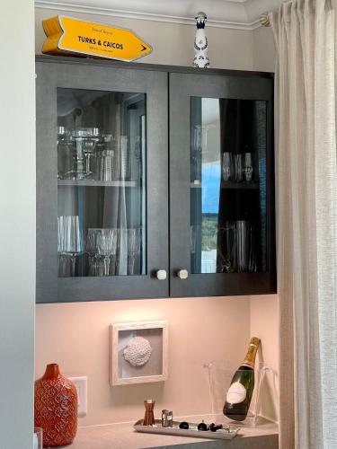 a kitchen cabinet with glasses and a bottle of wine at Seas the Day TCI -Sonos, Covered Balcony, hot tub in Wheeland Settlement