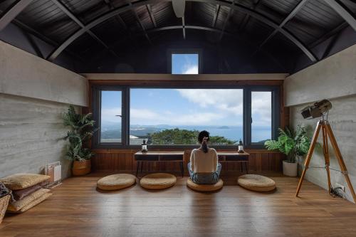 a man sitting in a room with a large window at Jiufen The Ocean Theory in Jiufen