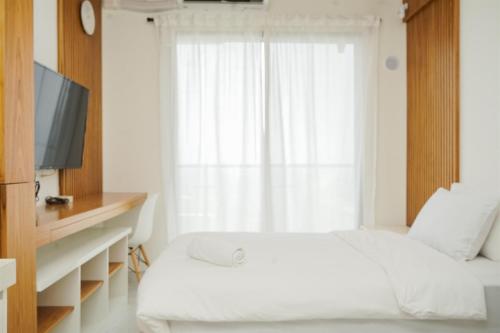 une chambre avec un lit blanc et une fenêtre dans l'établissement Comfy Studio at Sky House BSD Apartment By Travelio, à Tangerang
