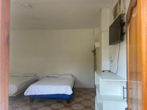 a small room with two beds and a tv at Hostería del Puerto in Puerto López