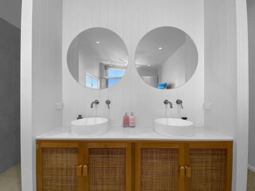Dos lavabos en un baño con dos espejos en Casa del Sol, en Nelly Bay