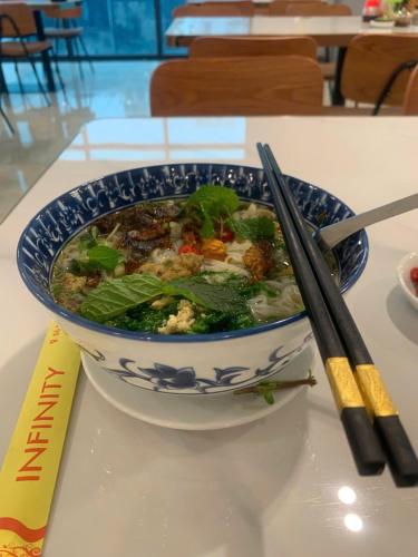 un tazón de comida sentado en una mesa con palillos chinos en Infinity Hotel, en Thái Bình