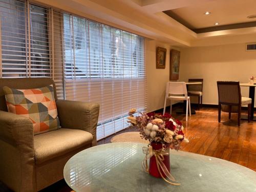 a living room with a table with a vase of flowers at Happiness Hotel in Taipei