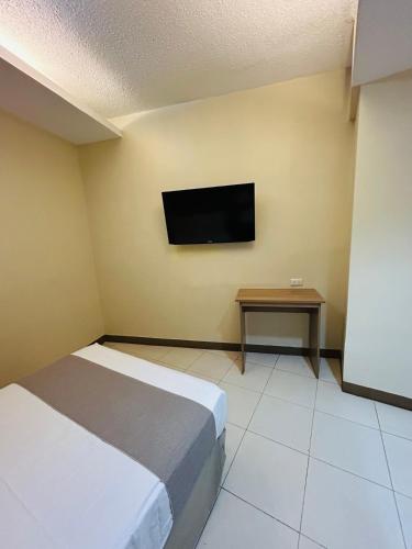 a bedroom with a bed and a tv on the wall at The New View by Ecotel - Cebu in Cebu City