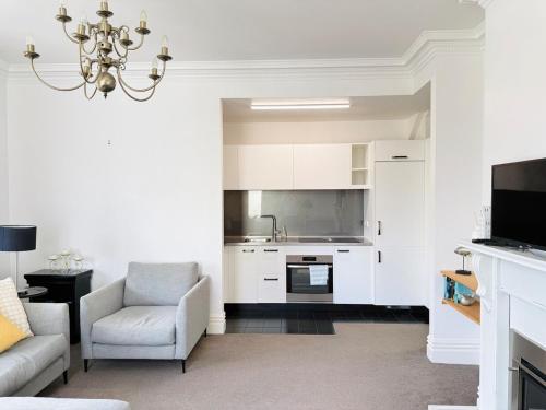 a living room with a chandelier and a kitchen at A Central City Historic Escape in Wellington