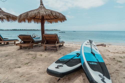 a kayak on the beach next to an umbrella and chairs at Sunscape Villa - Beachfront and private pool in Gili Air