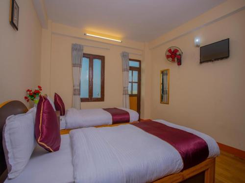 a bedroom with two beds and a tv on the wall at Hotel Black Stone and Snooker House in Dhulikhel