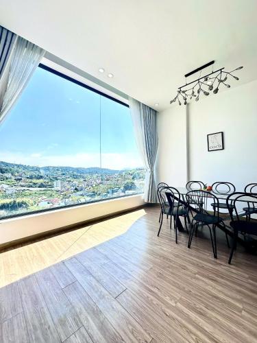 a dining room with a table and chairs and a large window at Gấu House Villa in Da Lat
