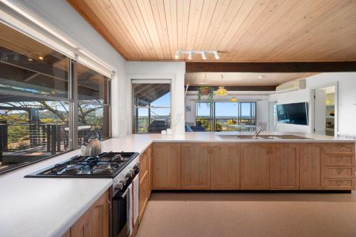 a kitchen with wooden cabinets and a stove top oven at Cloud Valley Estate -Chalet in Bowraville