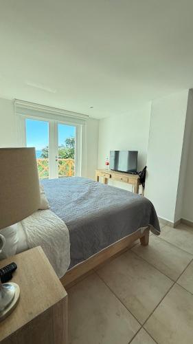 ein Schlafzimmer mit einem Bett, einem Schreibtisch und einem Fernseher in der Unterkunft Bello departamento con vistas al mar in Acapulco
