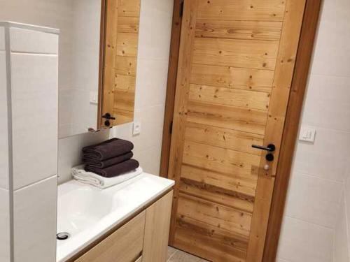 La salle de bains est pourvue d'un lavabo et d'une porte en bois. dans l'établissement Chalet 3 pièces avec WIFI, parking et terrasse à Châtel - FR-1-676-205, à Châtel