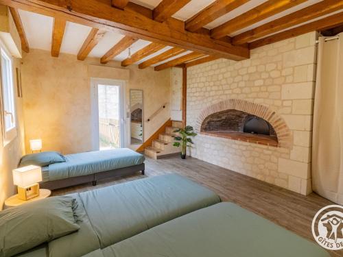 a bedroom with two beds and a brick fireplace at Séjourner au cœur de la nature entre Tours et Angers - FR-1-622-101 in Saint-Philbert-du-Peuple