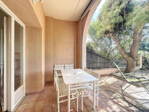une table et des chaises sur une terrasse avec un arbre dans l'établissement Appartement T3 avec jardin, accès direct plage - FR-1-770-43, à Saint-Cyr-sur-Mer