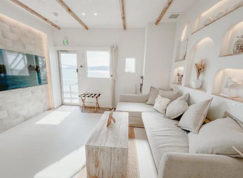 神戸市にあるBeachHouse Gerageraのソファとテーブルのある白いリビングルーム
